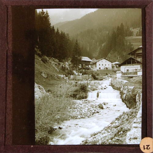 Chalet-style buildings and river in mountainous landscape