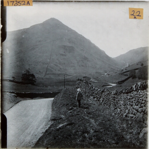 Man standing by road in mountainous landscape