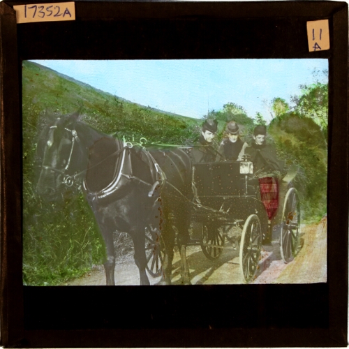 Three women riding in horse-drawn carriage