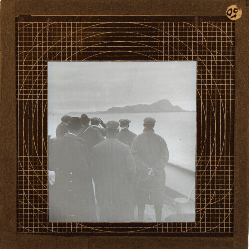 Group of men looking at coastline from ship
