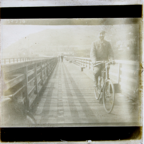 Man riding bicycle across wooden bridge