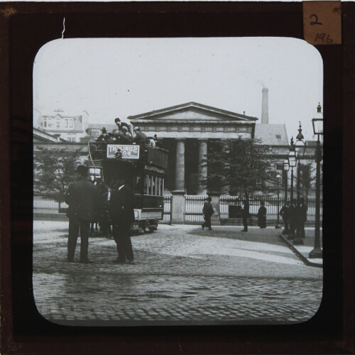 Horse-drawn tram waiting outside large building with columns – secondary view of slide