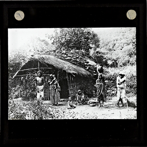 Group of native people standing outside house