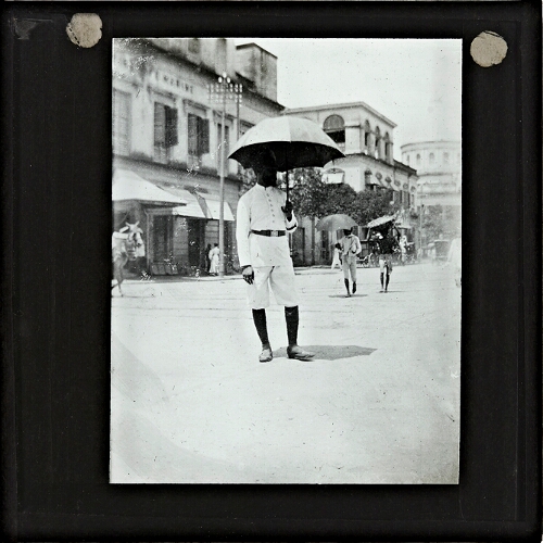 Man wearing uniform carrying umbrella in street