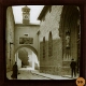 [Archway and church entrance in street in unidentified town]