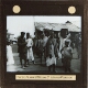 [Group of men and children standing in street of town or village]