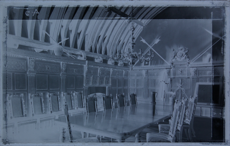 Interior of old room with large table and display of weapons