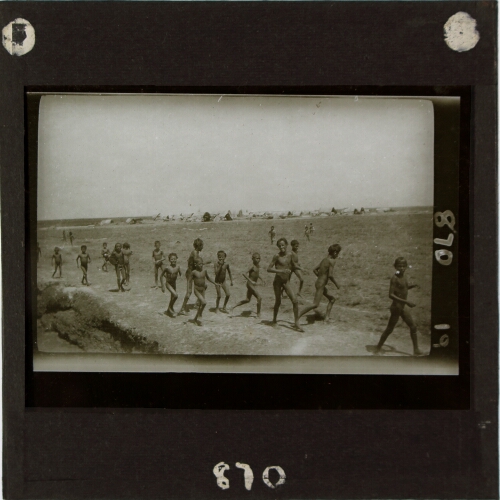 Group of boys running with camp in background