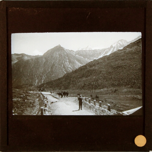 People walking up road in mountainous landscape