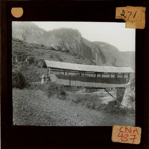 Covered bridge over river in mountainous landscape