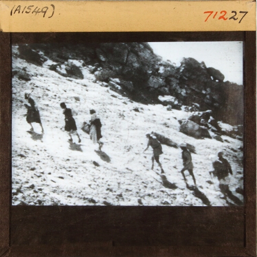 Group of men ascending slope in mountainous landscape