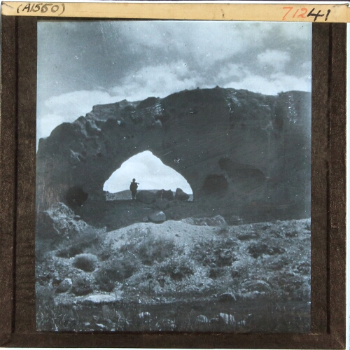 Man standing under arched rock formation
