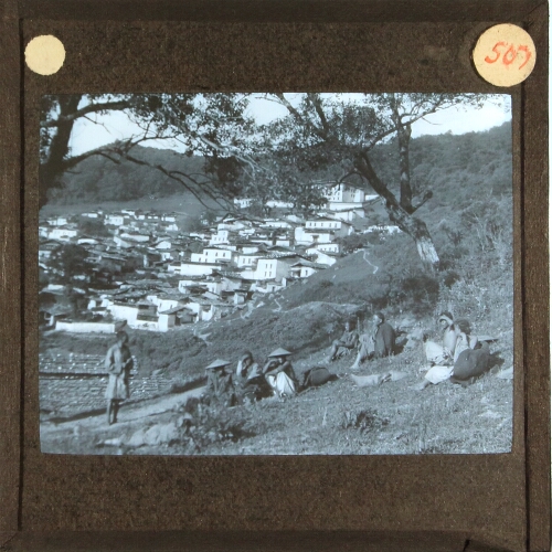 Group of people sitting on hillside near settlement