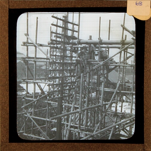 Men working in scaffolding structure by telegraph pole