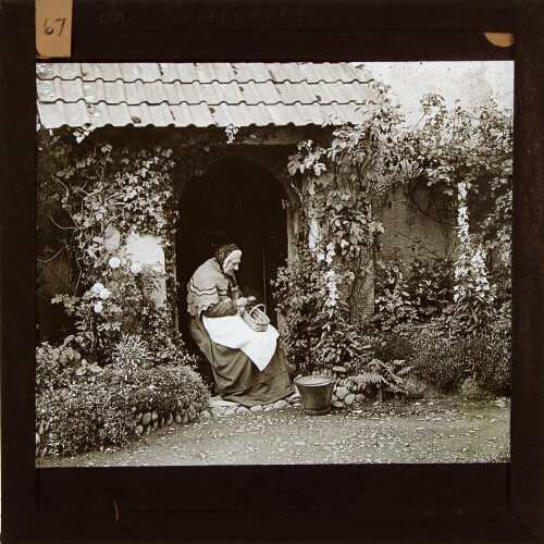 Old woman sitting at doorway of cottage