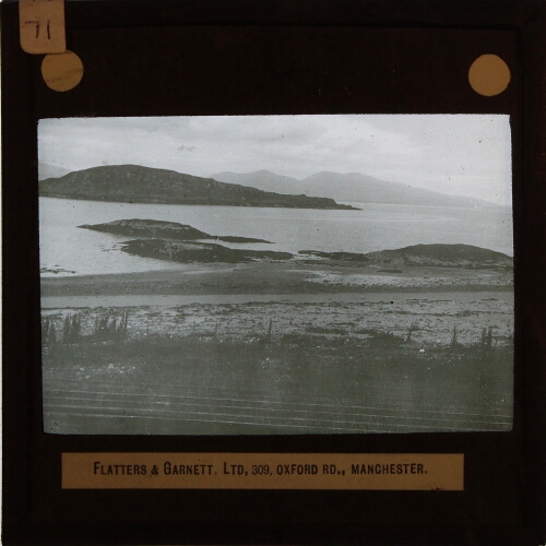 View of shore with islands and distant mountains