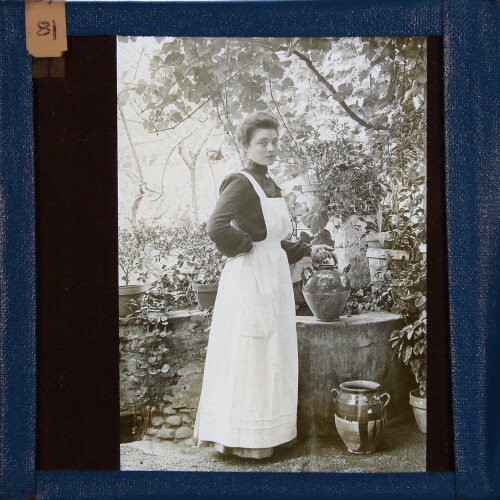 Young woman wearing apron with watering can