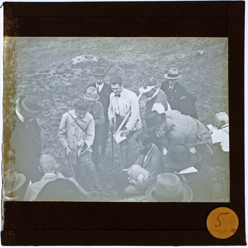 Group of people in seemingly unsuitable cloths, digging in the field