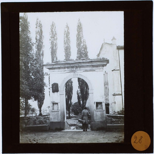 Woman with luggage at archway at the entrance of cemetery  or church yard