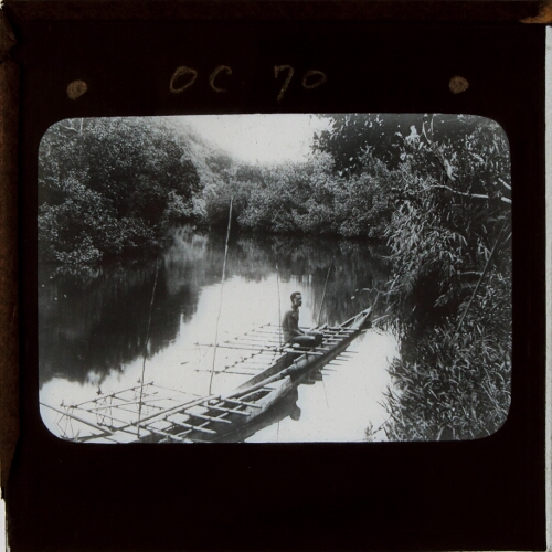 Man sitting in outrigger canoe on river