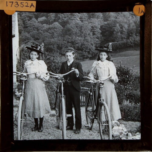 Two girls and boy holding bicycles