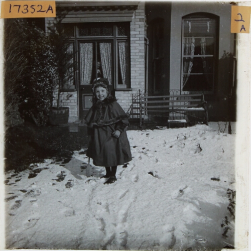 Girl standing in snow in garden of house