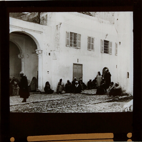 Group of men sitting in street outside building
