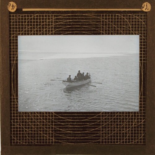 Group of men in rowing boat approaching ice shelf