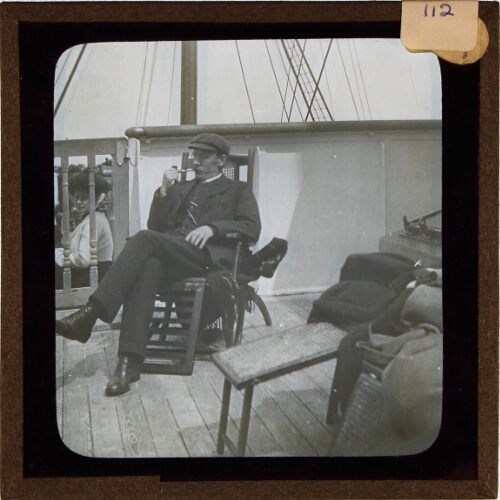Man smoking pipe in chair on deck of ship