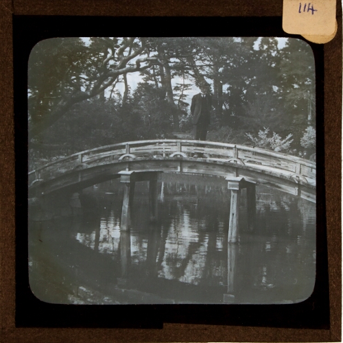 Man standing on bridge over pond or river