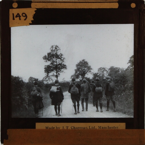 Group of men with rucksacks walking along country lane