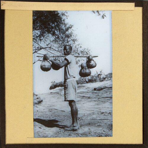 African man carrying water containers on shoulder