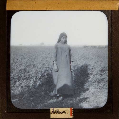 African woman standing by field of crops