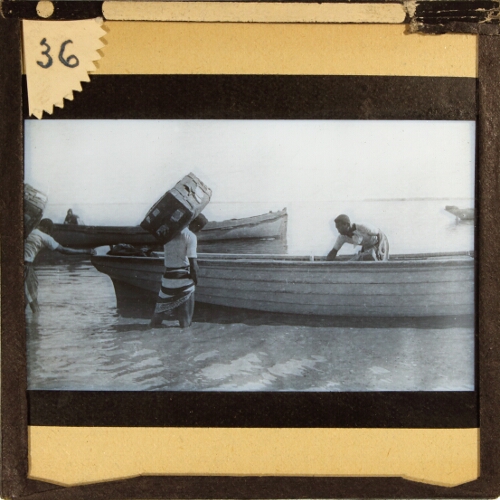 Men loading large trunks into small boat