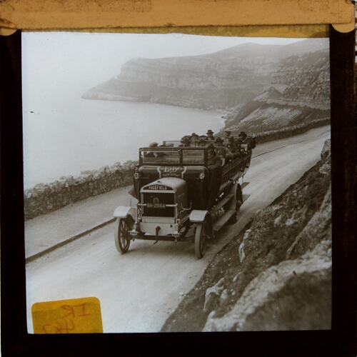 Group of people riding in charabanc along coastal road