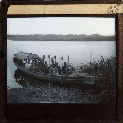 Group of people with oars sitting in boat at river or lake shore