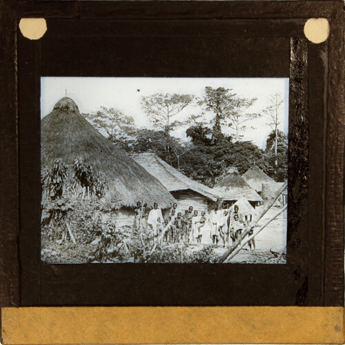 Group of people standing in village of thatched houses