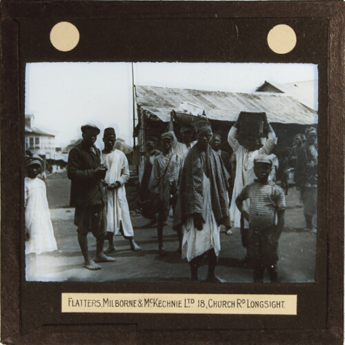 Group of men and children standing in street of town or village