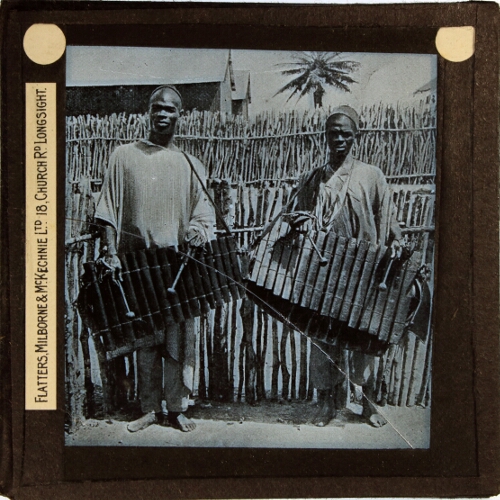 Two men carrying Balangi musical instruments