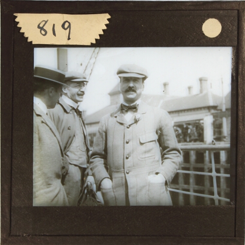 Three men standing on deck of ship