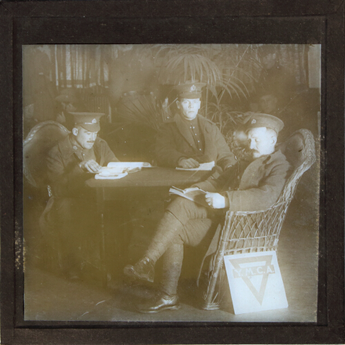 Three soldiers sitting in chairs around table