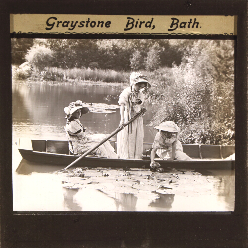 Three young women looking at water lilies from punt