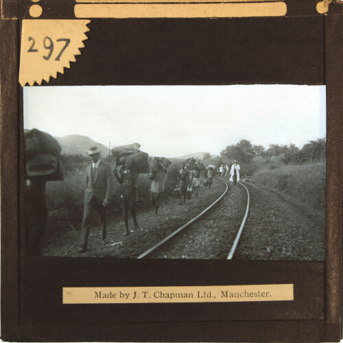 Group of people walking with luggage along railway track