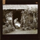 [Old woman sitting at doorway of cottage]