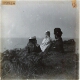 [Man and two girls lying on cliff top]