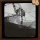 [Two crew members working on lifeboat davit of ship]