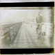 [Man riding bicycle across wooden bridge]