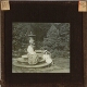 [Woman and girl sitting on base of sundial in garden]