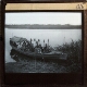 [Group of people with oars sitting in boat at river or lake shore]